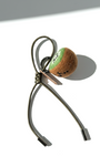 Artisan needle-felted kiwi slice charm featuring an olive green cord and silver-toned accents.