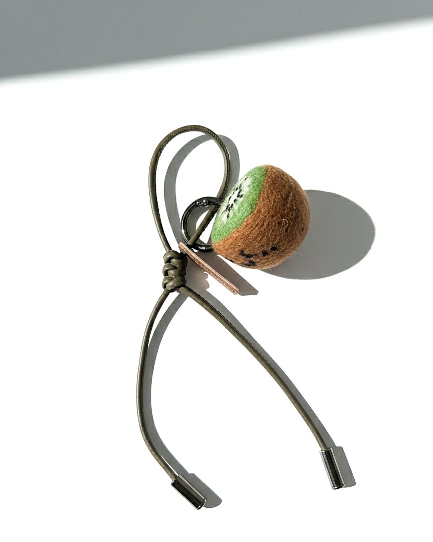 Artisan needle-felted kiwi slice charm featuring an olive green cord and silver-toned accents.