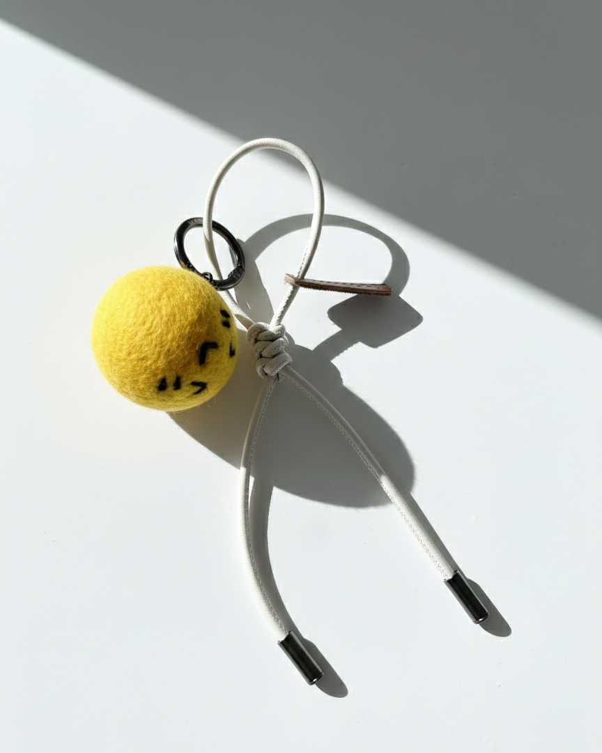 Handmade smiley face lemon felt charm with cream white cord and metal tips.