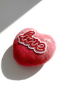 Close-up of a decorative wool felt heart magnet showing the fuzzy texture of the finest Merino wool and an artistic red-to-pink ombre finish.