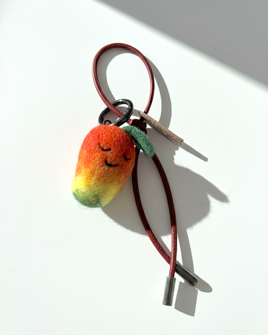 Miniature needle-felted mango keychain with dark red burgundy cord.