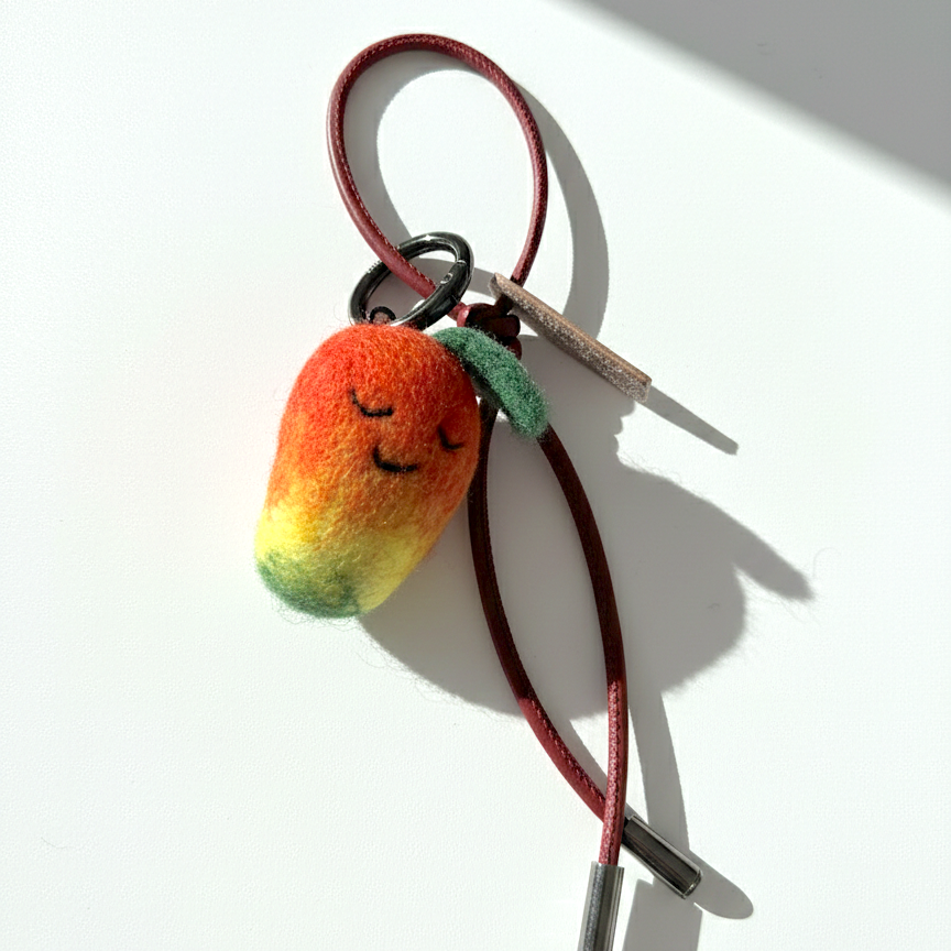 Miniature needle-felted mango keychain with dark red burgundy cord.