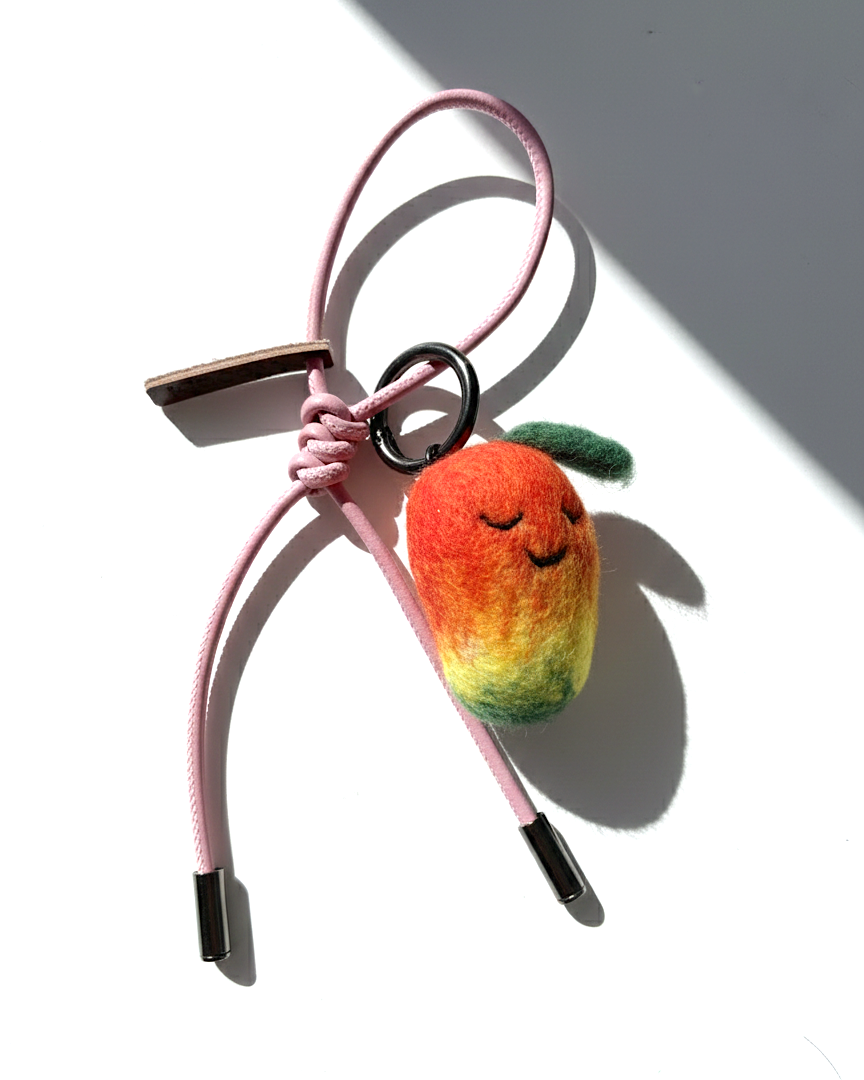 Needle-felted mango bag charm with pink cord and silver aglets.