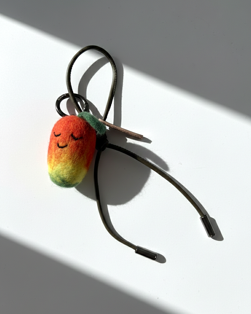 Cute needle-felted mango smiley face plush charm with olive green cord.