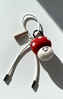 Artisan felted red toadstool keychain accessory with a cream white cord and metal tips.