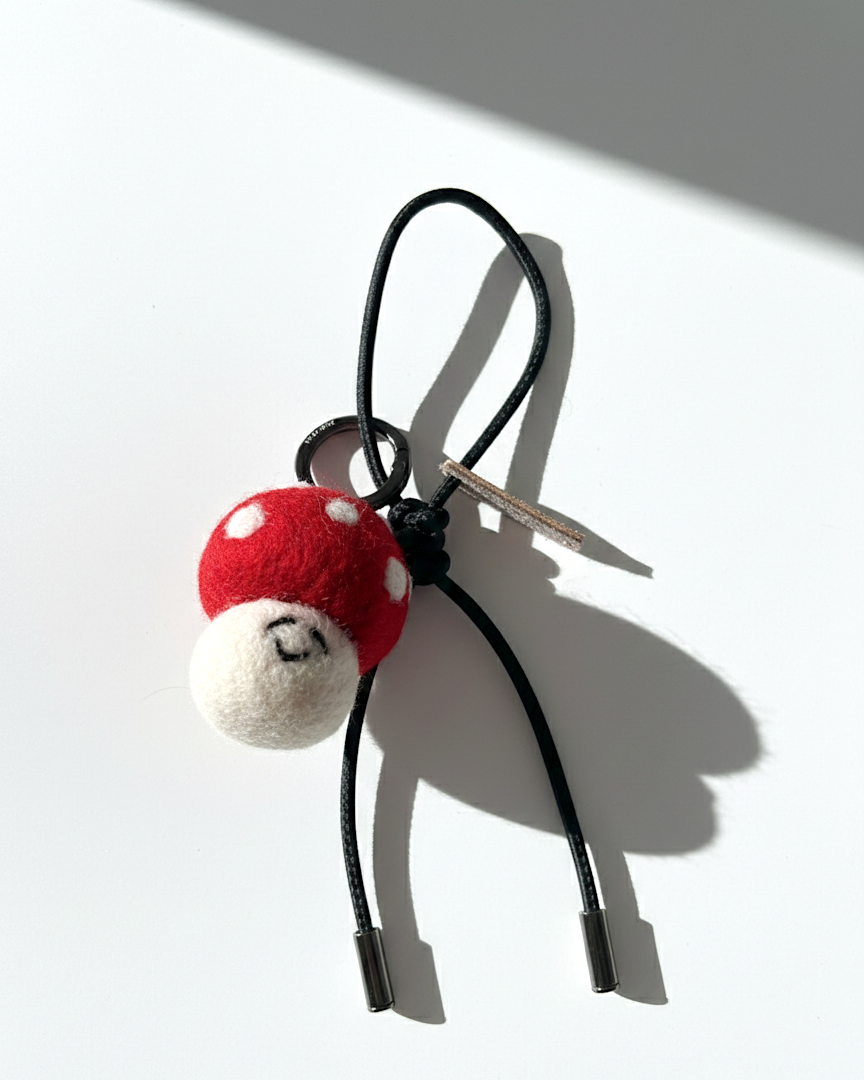 Miniature needle-felted mushroom plush charm with a black leather cord and silver hardware.