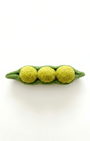 Felted green pea pod with three yellow peas on a white background