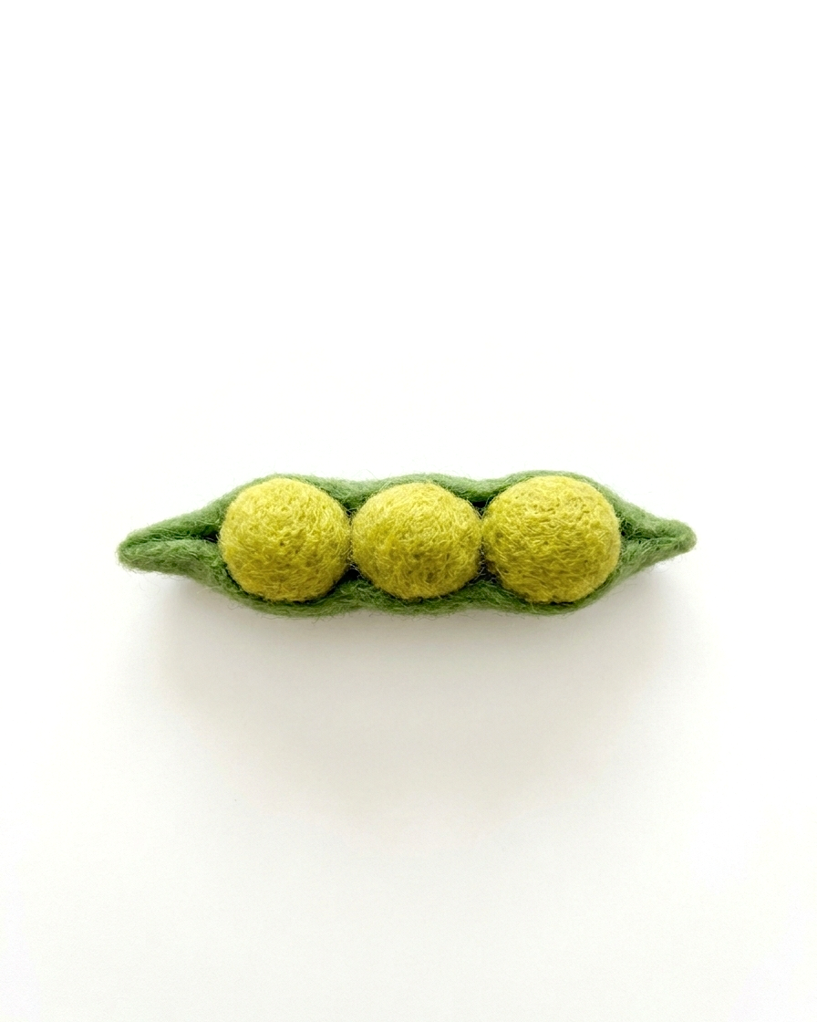 Felted green pea pod with three yellow peas on a white background