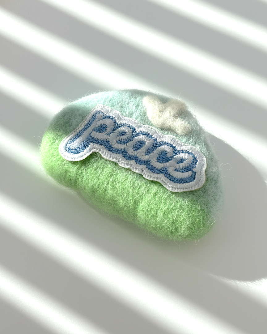 Mint green needle-felted wool magnet with stitched Peace patch, soft rounded handmade fridge decor