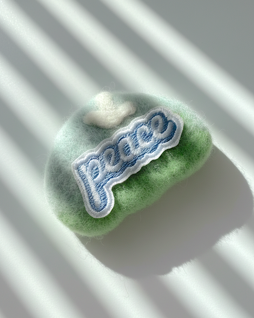 Handcrafted merino wool fridge magnet in green gradient tones featuring Peace embroidery patch