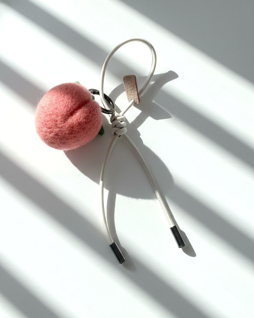 Handcrafted wool felt strawberry bag charm back view with cream leather loop strap, realistic needle felt fruit keychain on minimalist white background