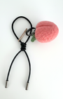 Close-up of handmade wool felt strawberry bag charm with black leather cord and metal tips, sustainable artisan fruit keychain in soft shadow lighting