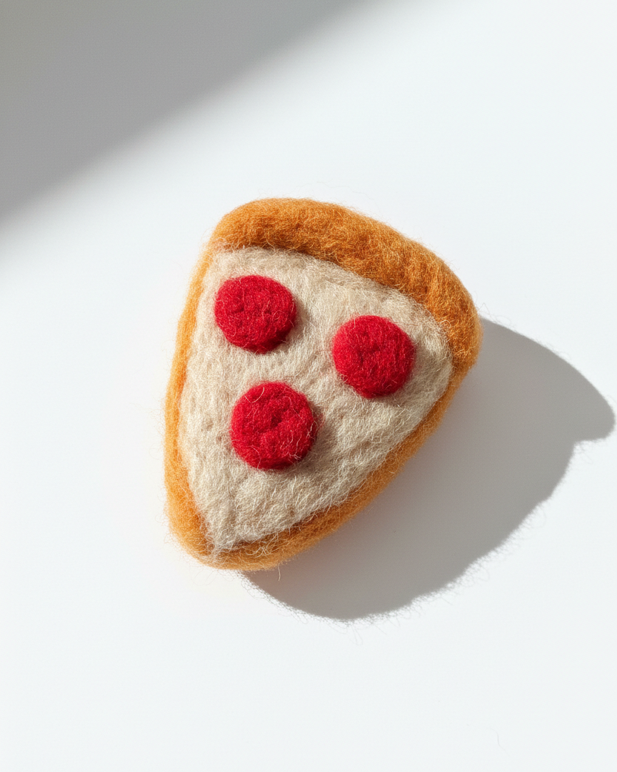 Handmade wool pepperoni pizza slice fridge magnet, needle-felted with soft texture on white background