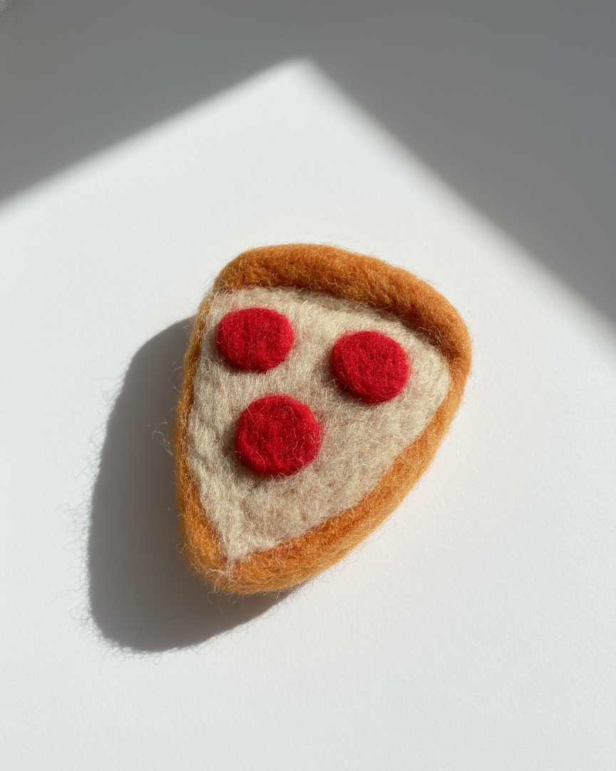 Close-up of handmade wool pepperoni pizza slice fridge magnet showing felt texture and rounded edges