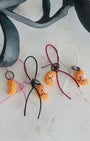 Panning video showing the full color collection of needle-felted orange slice bag charms with four leather strap options: white, pink, black, and red, arranged on a marble surface.