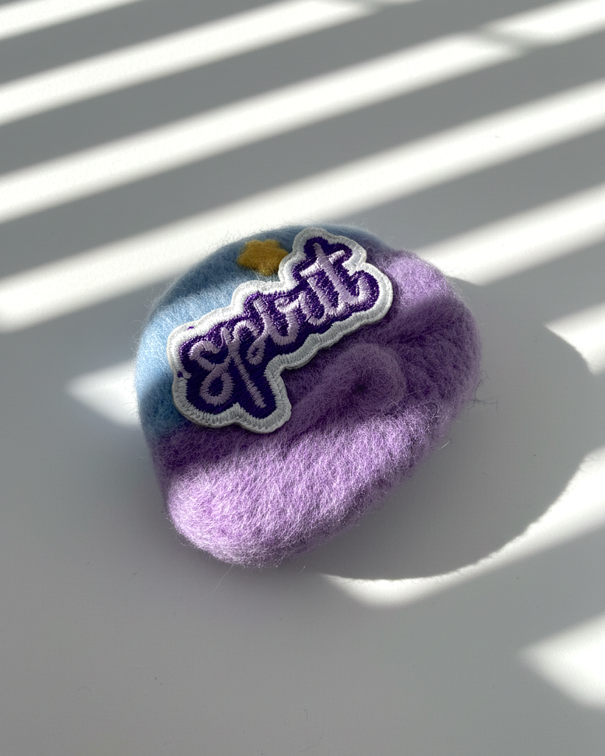 Purple and blue needle-felted wool magnet with stitched Spirit patch, soft rounded shape, handmade fridge decor