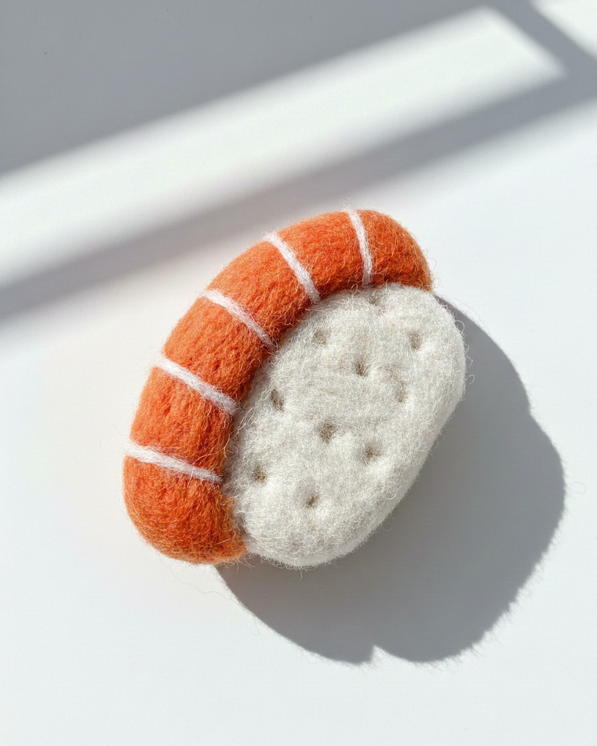 Close-up of handcrafted wool sushi magnet, needle felted salmon sushi with detailed wool texture