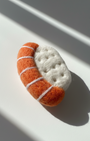 Handmade needle felted sushi wool magnet with orange salmon and white rice, minimalist product photo in natural light