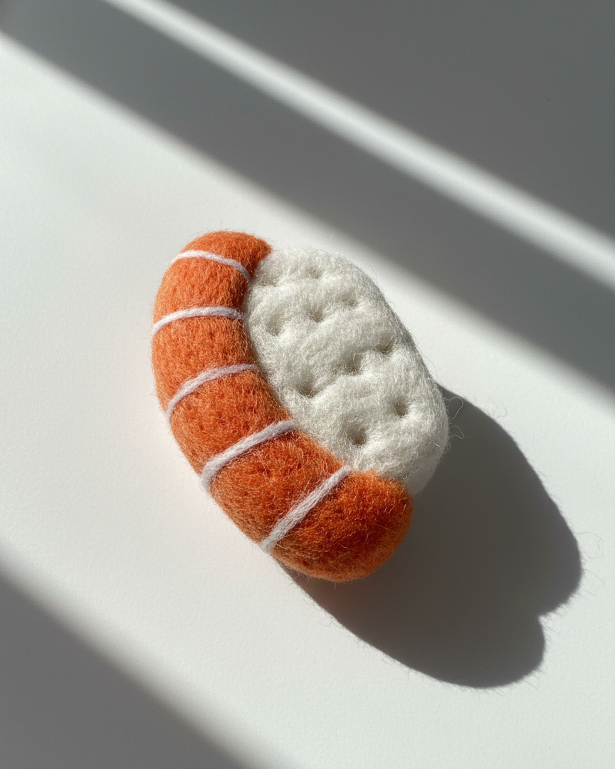 Handmade needle felted sushi wool magnet with orange salmon and white rice, minimalist product photo in natural light