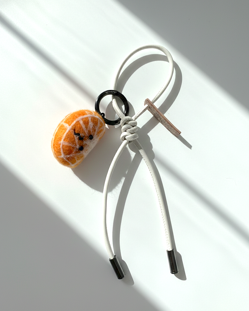 Handmade needle-felted orange slice keychain with white leather loop and metal ring