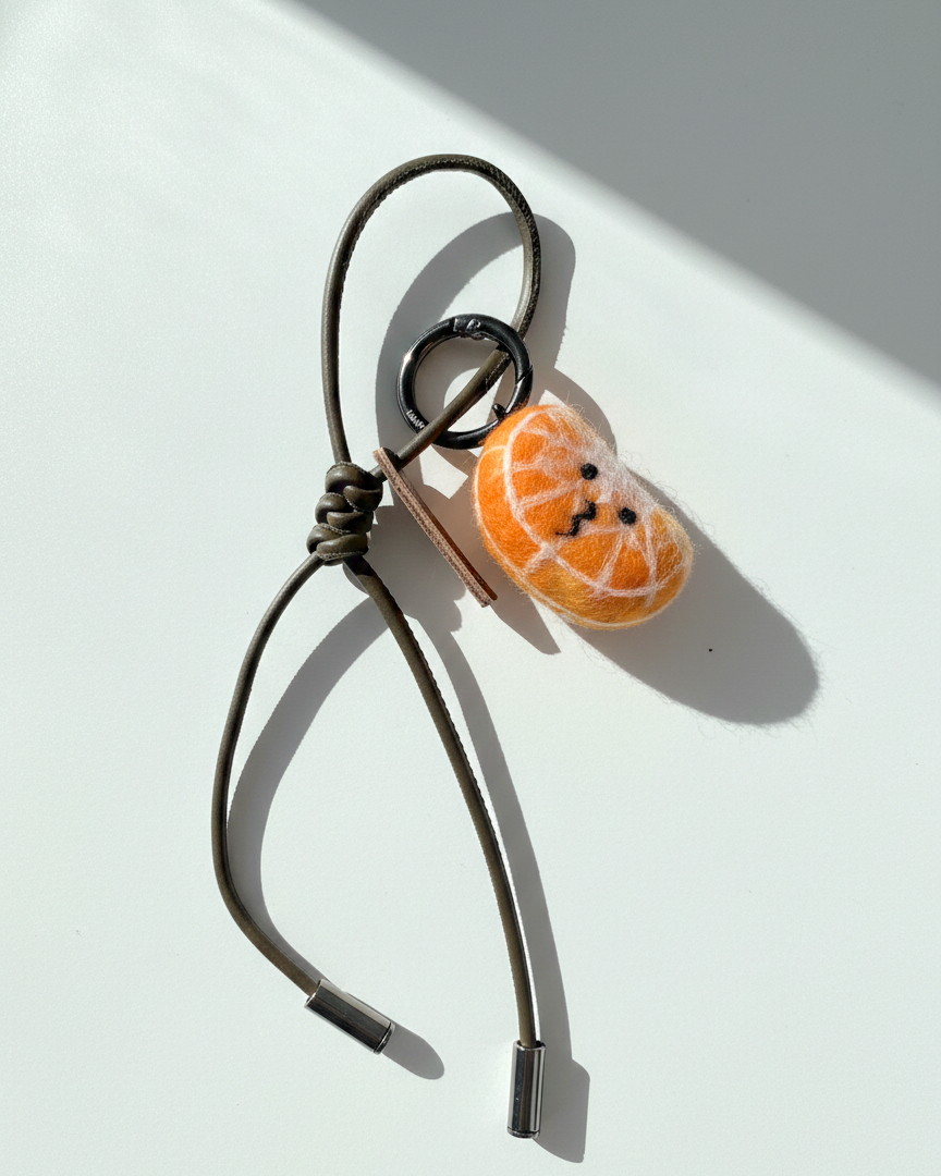 Wool felt citrus slice charm with olive leather loop, handmade fruit keychain accessory
