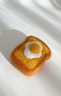 Needle-felted wool egg toast magnet shown from above with soft felt texture