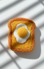Handmade wool toast magnet with fried egg detail, felted by hand on white background